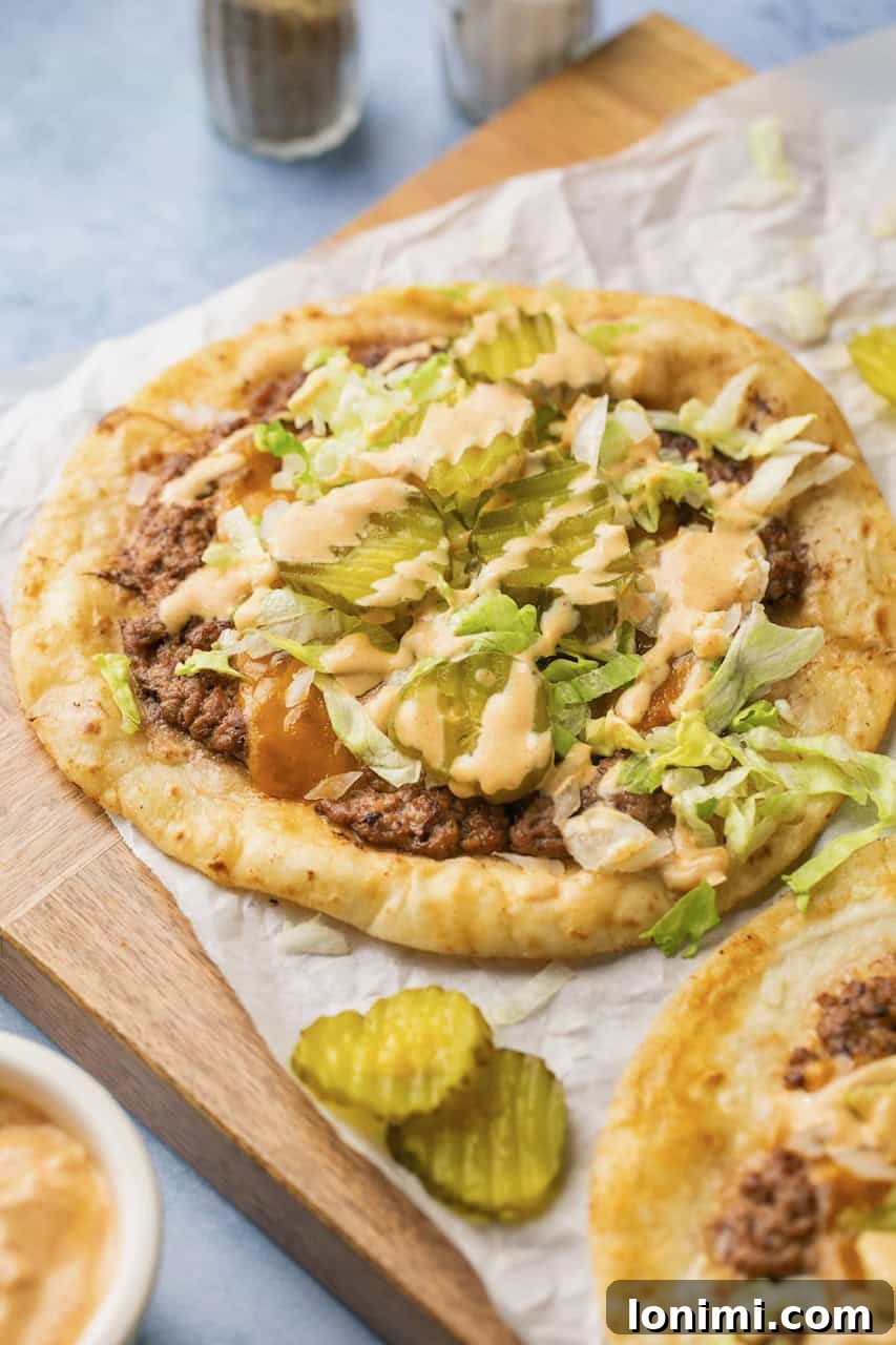 A close-up of big mac tacos topped with lettuce, pickles, cheese, and sauce, served on parchment paper for a fast-food inspired look.