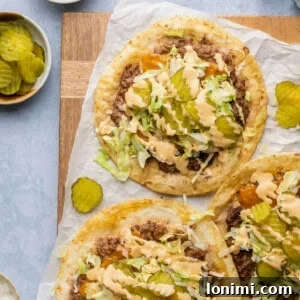 smash burger big mac tacos on parchment paper topped with lettuce pickles and sauce