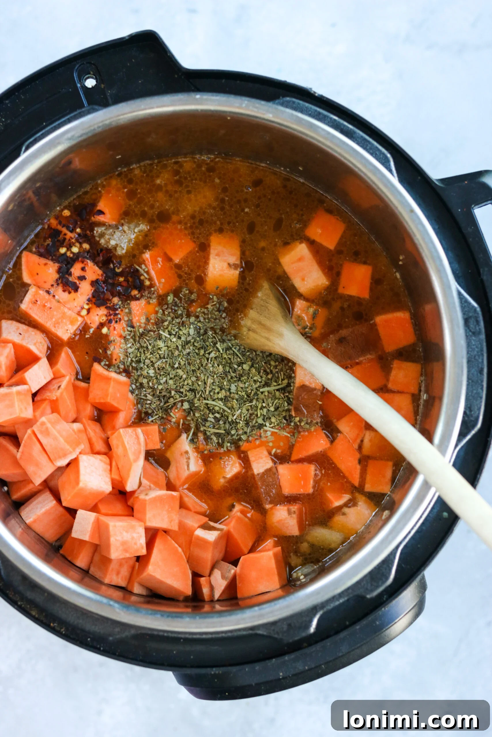 Hearty Whole30 Paleo Gluten Free Zuppa Toscana 5 Diced sweet potatoes being added to the Instant Pot with sautéed sausage and other soup ingredients