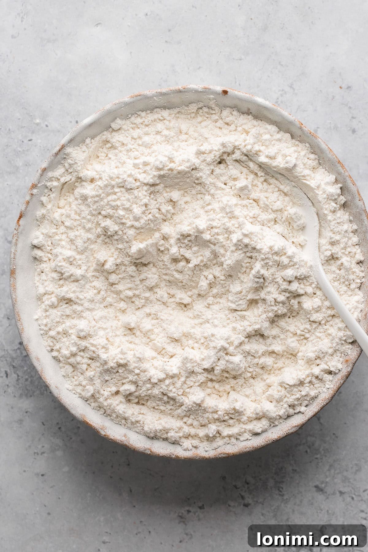 Gluten-free flour and baking soda in a mixing bowl, ready for whisking.
