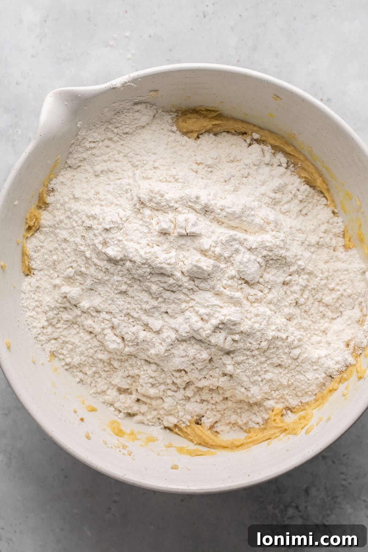 Dry ingredients being added to the bowl of wet ingredients (sugar, egg, butter).