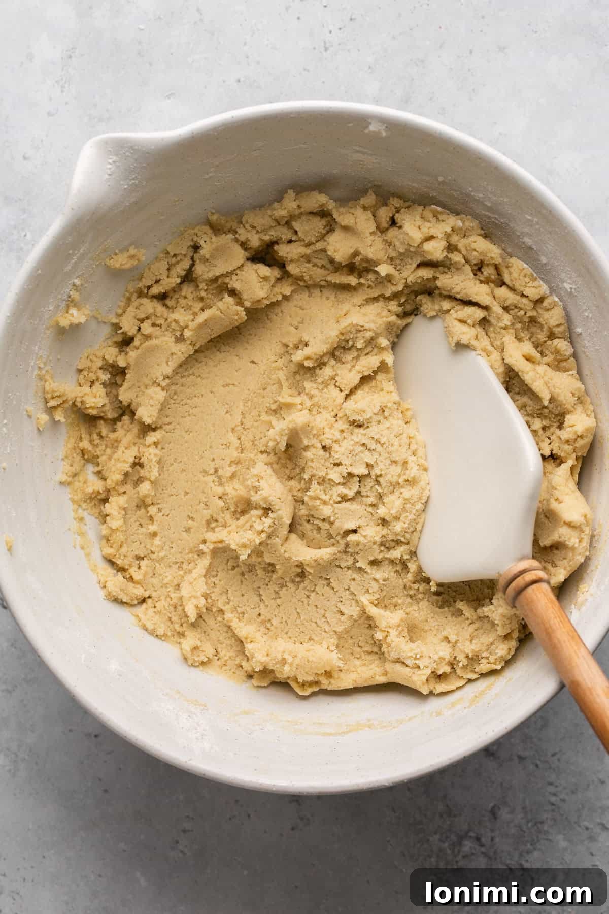 Cookie dough in a bowl with a white spatula, ready for chilling.