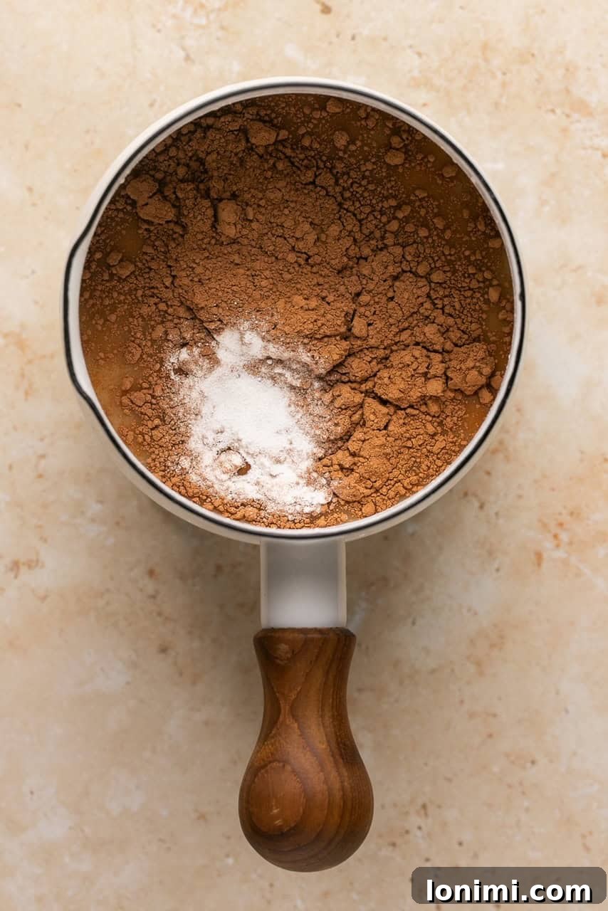Collagen Cocoa Elixir 4 a small sauce pan with collagen, broth, cocoa powder, and maple syrup in it