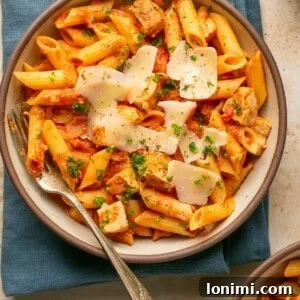 Chicken and penne vodka in a bowl topped with parmesan and parsley