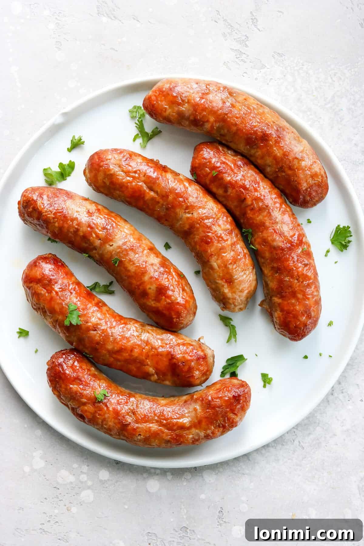 Crispy air-fried Italian sausages on a white plate, garnished with fresh parsley.
