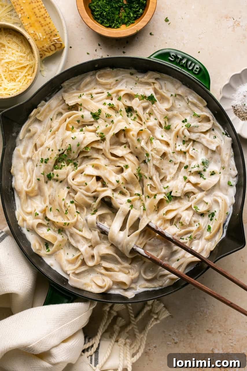 cottage cheese alfredo in a green and black skillet with tongs