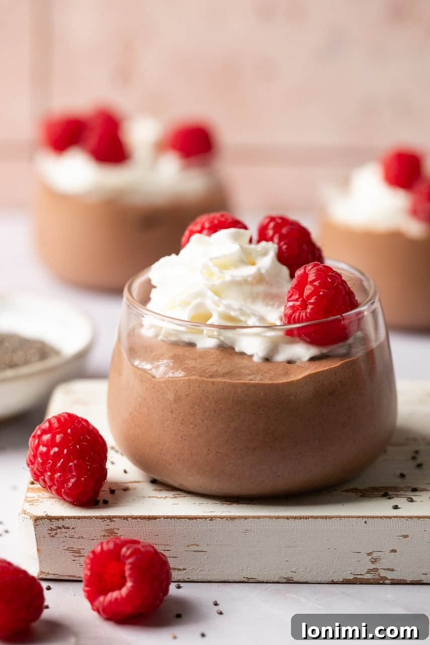 Protein chia seed pudding in a jar, topped with whipped cream and berries, ready to serve.