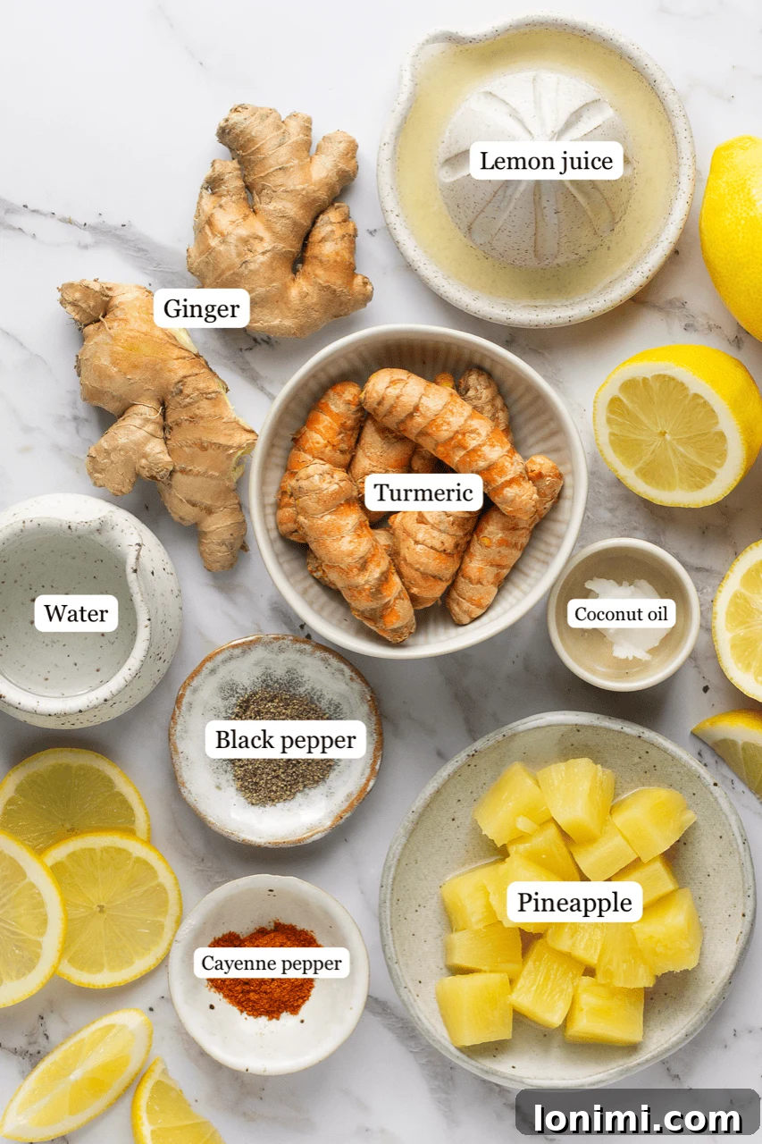 Fresh ingredients for lemon ginger turmeric shots including lemon, ginger, turmeric root, pineapple, cayenne, and black pepper
