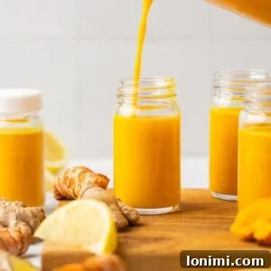 Lemon ginger turmeric pineapple shot being poured into a shot glass