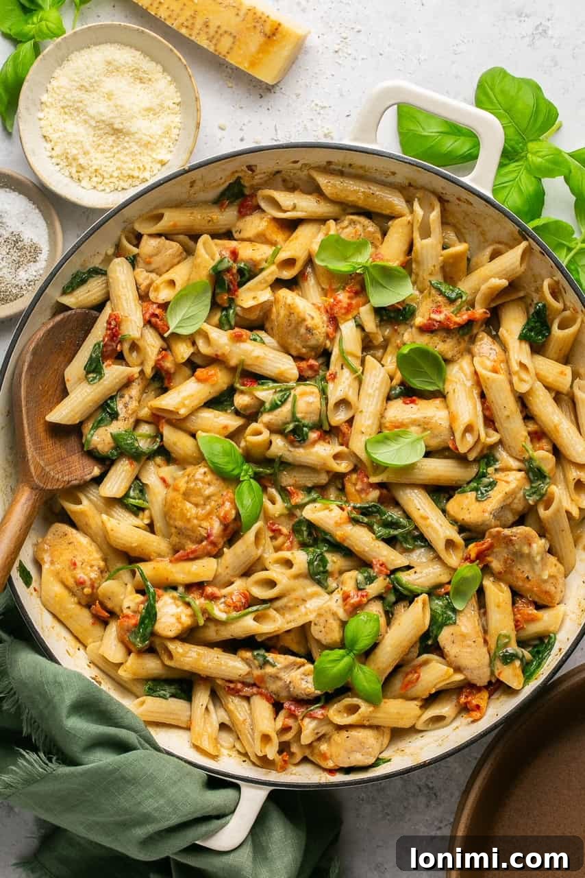 Creamy sun-dried tomato chicken pasta in a bowl with spinach and penne, ready to serve.