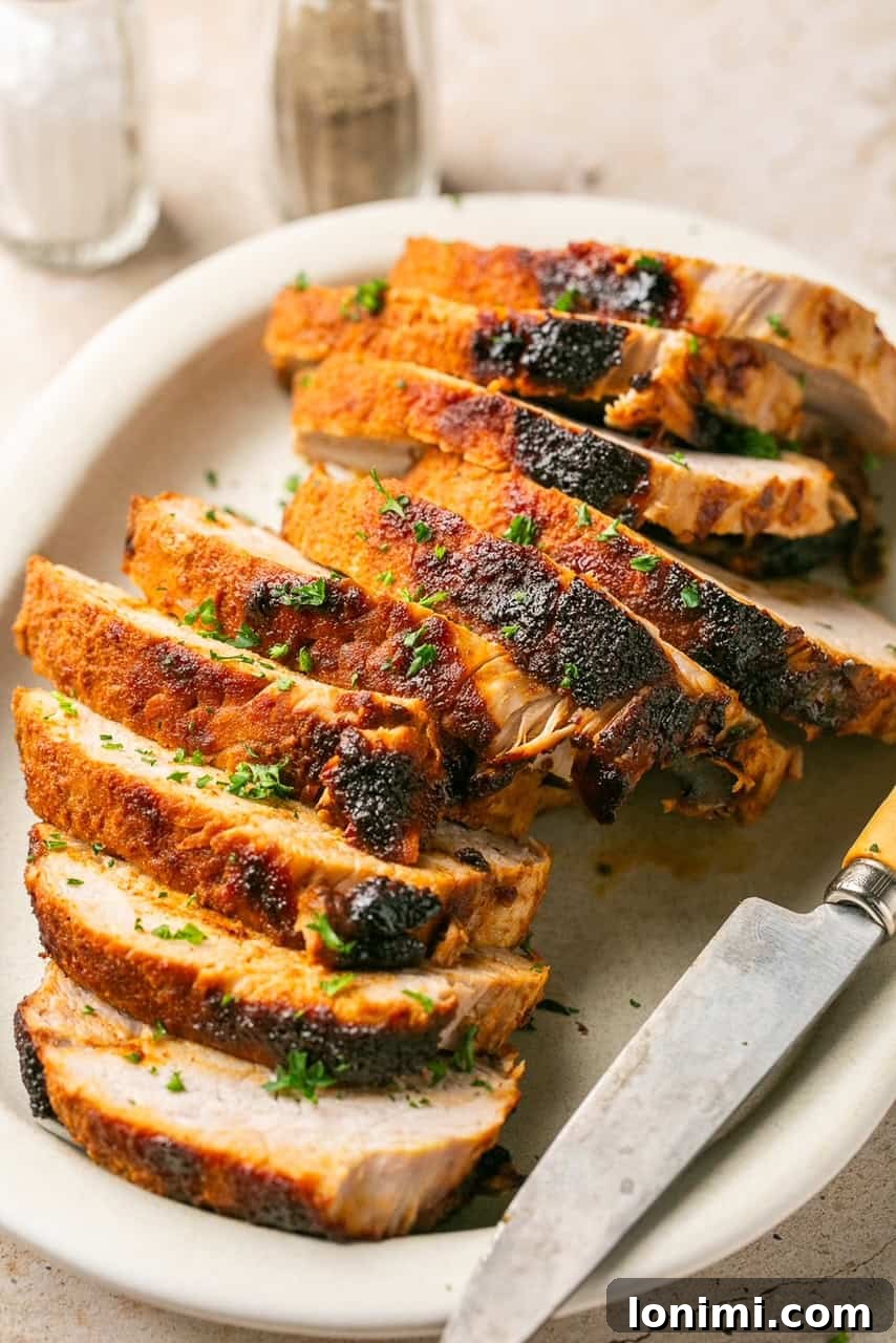 pork loin sliced on a white platter with a knife