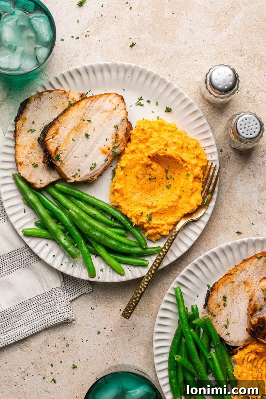 2 plates with sliced pork roast, mashed sweet potatoes and green beans