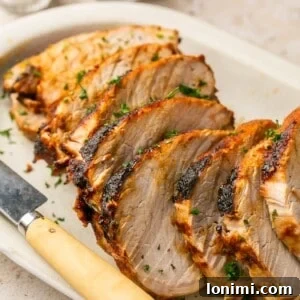 air fryer pork roast sliced on a white platter with a knife
