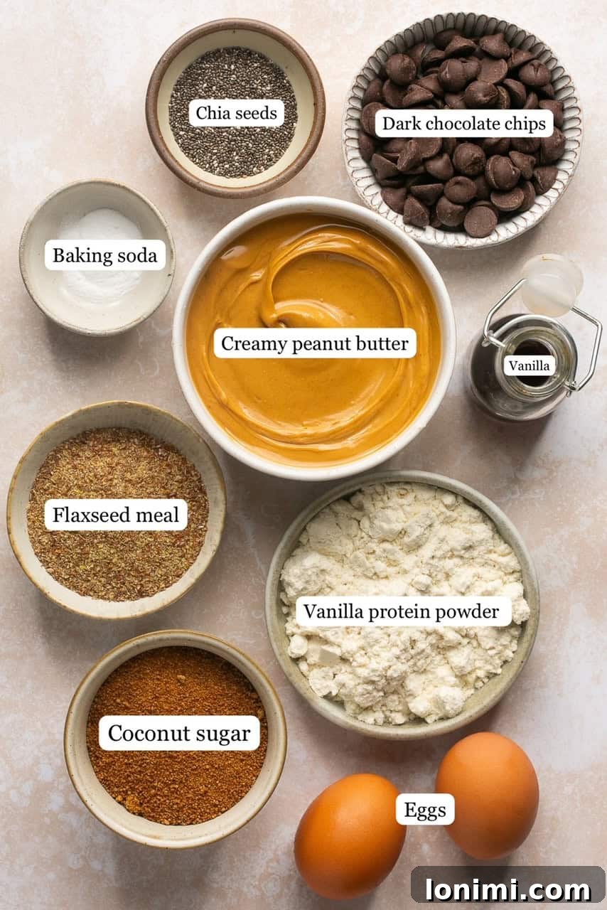 Irresistible Protein Peanut Butter Chocolate Chip Cookies 3 Various ingredients for protein cookies laid out in small bowls, including peanut butter, eggs, vanilla, coconut sugar, protein powder, flax seeds, chia seeds, baking soda, and chocolate chips.