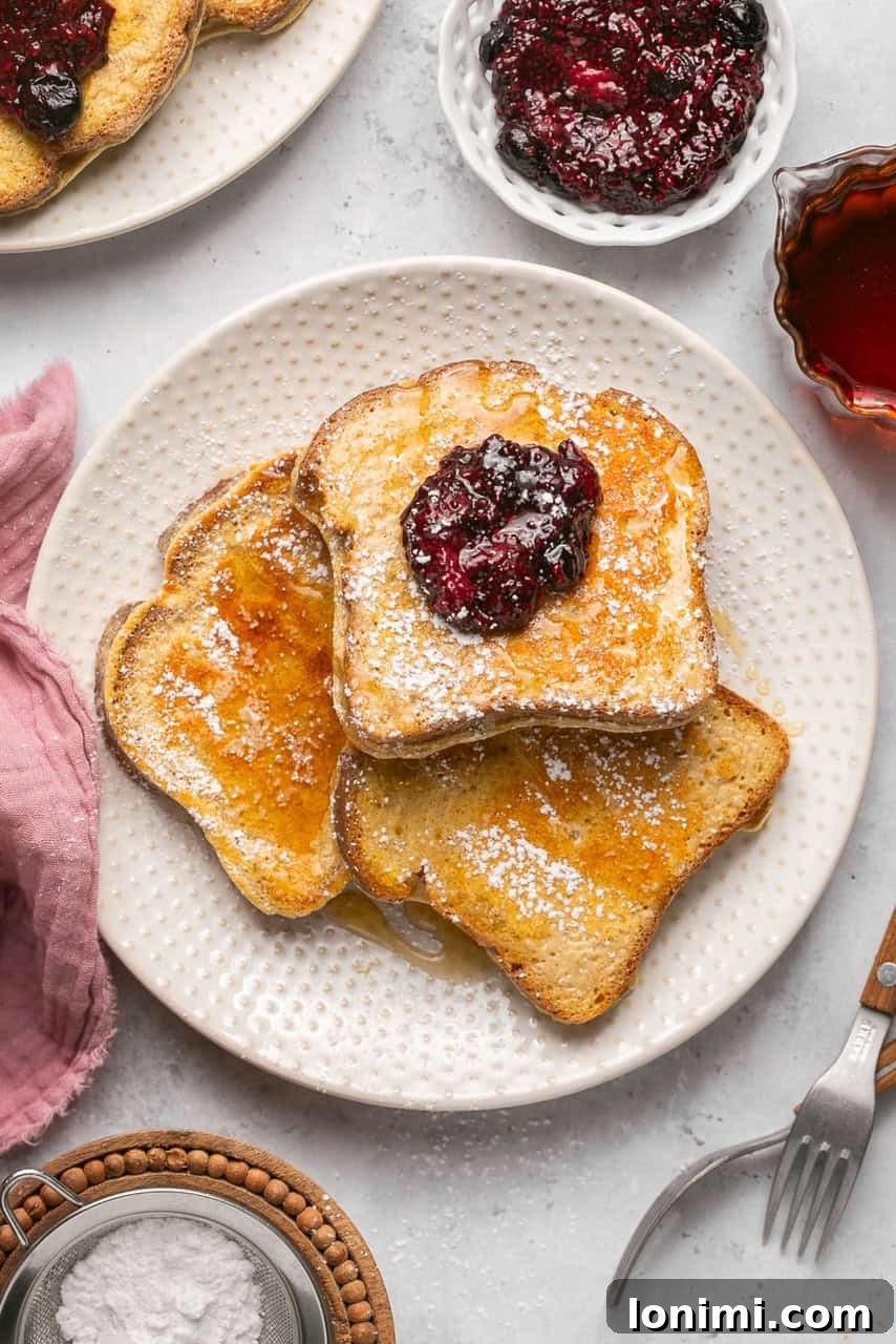 Delicious protein french toast on a plate topped with vibrant chia jam and a dusting of powdered sugar