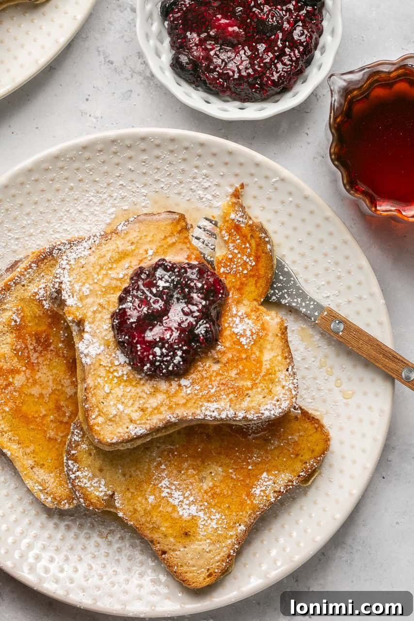 Three slices of perfectly cooked protein french toast on a white plate with a fork, ready to eat