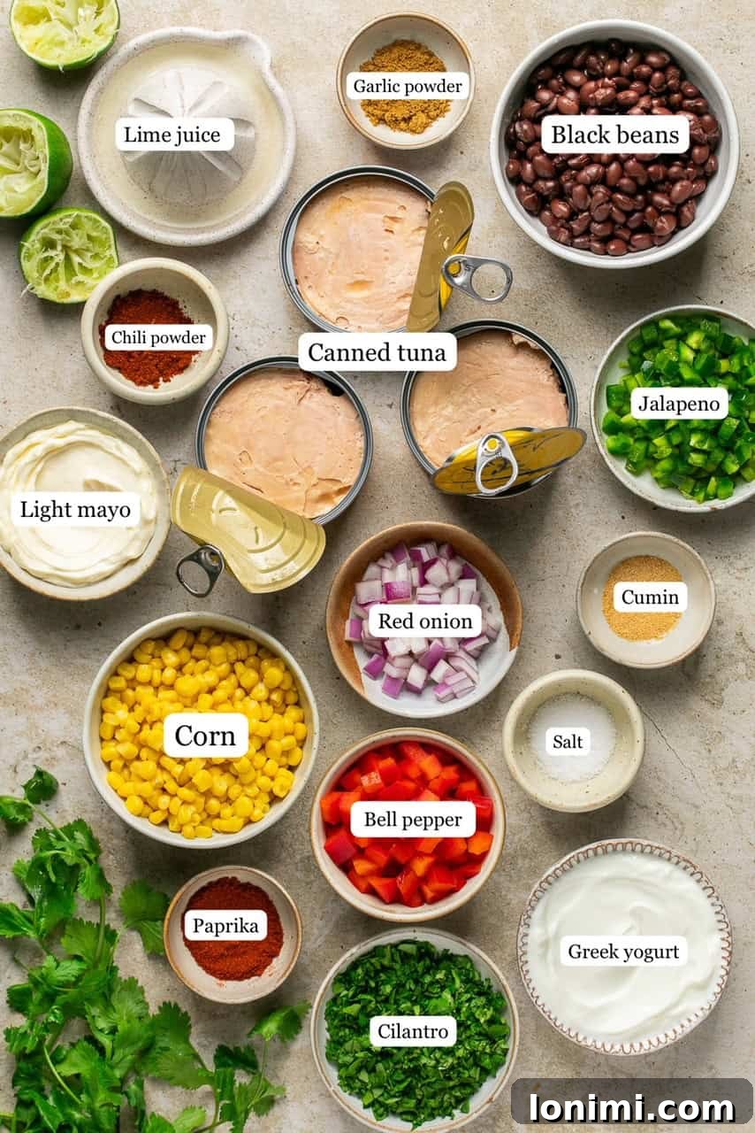 Vibrant Healthy Mexican Tuna Salad 3 All the ingredients for Mexican tuna salad laid out in small, labeled bowls on a wooden surface.