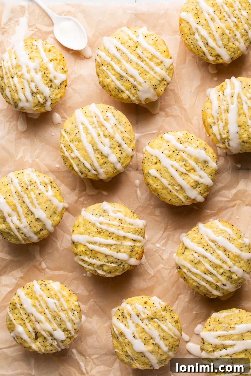 Gluten-free lemon poppyseed muffins arranged on a piece of parchment paper, beautifully drizzled with a sweet lemon glaze.