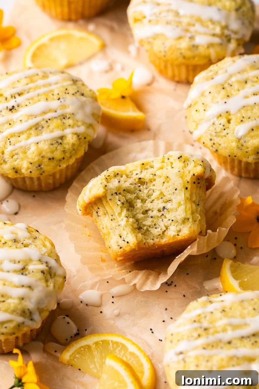 A close-up shot of a gluten-free lemon poppyseed muffin with a bite taken out, revealing its moist, tender interior.
