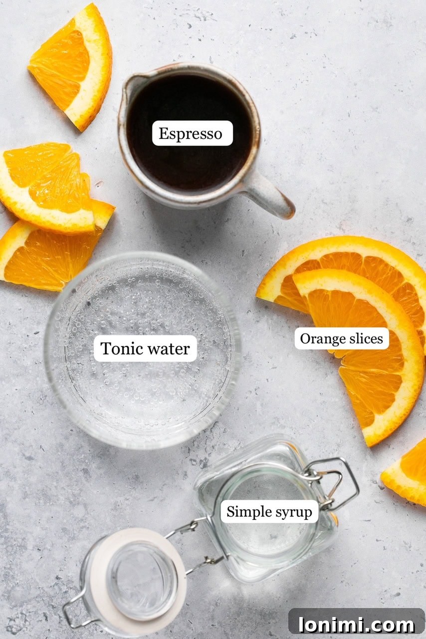 Individual ingredients for Espresso Tonic recipe laid out on a white surface, including espresso, tonic water, simple syrup, and an orange for garnish.