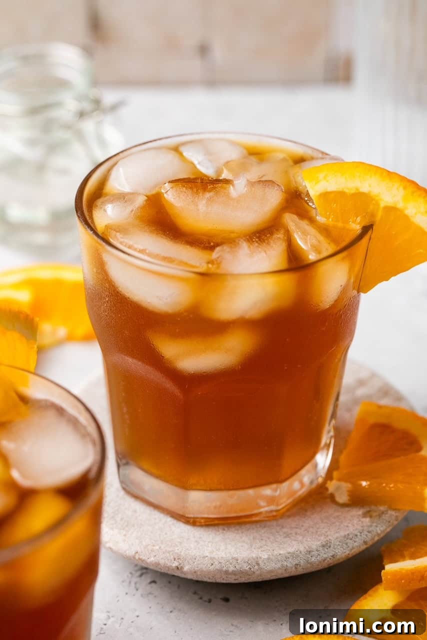 A close-up shot of a perfectly layered Espresso Tonic in a glass, showcasing the distinct coffee and tonic layers with ice and a citrus garnish.