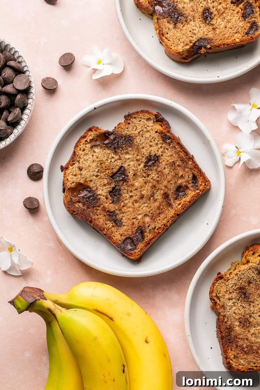 A perfectly sliced piece of protein banana bread with chocolate chips, presented on a white plate.