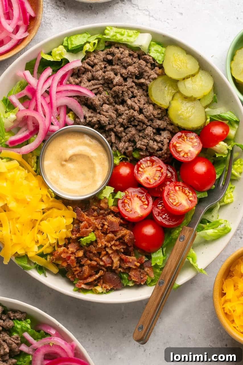 Bacon Cheeseburger Bowls Big Mac Style 6 A fully assembled cheeseburger bowl, featuring layers of lettuce, ground beef, cheese, tomatoes, pickles, bacon, pickled onions, and a generous drizzle of Big Mac sauce.