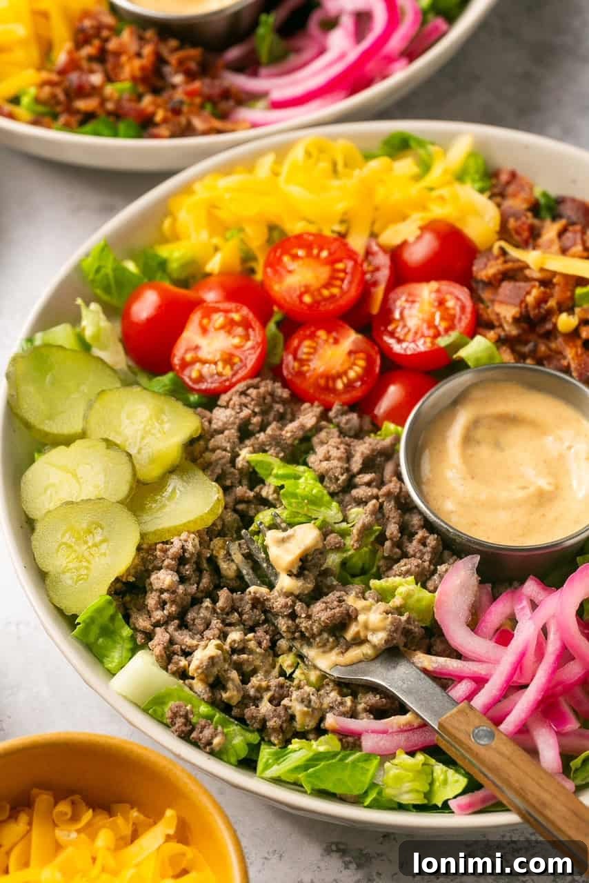 Bacon Cheeseburger Bowls Big Mac Style 7 A side view of a vibrant cheeseburger bowl, showcasing the layers of ingredients, with a fork poised for a bite.