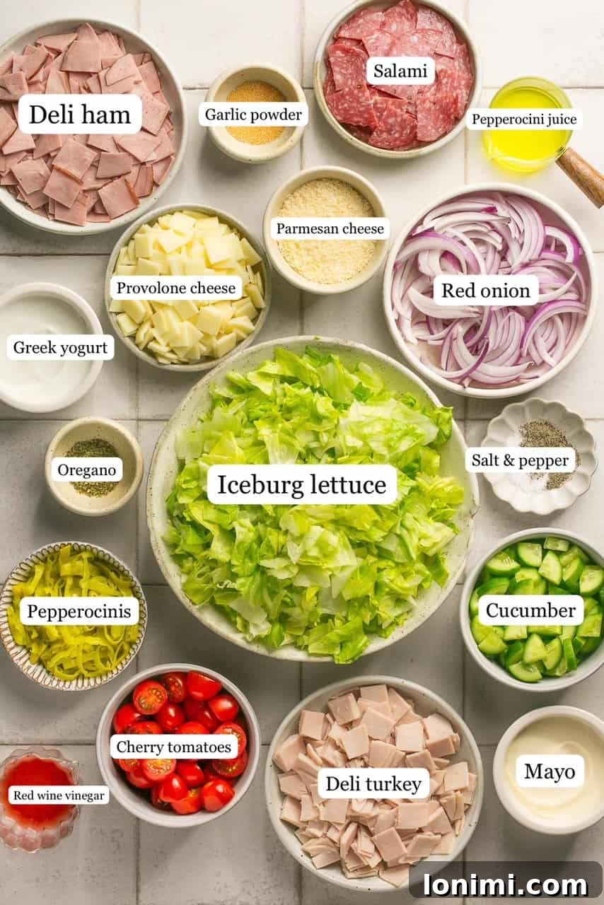 Labeled bowls showcasing the fresh ingredients for the Chopped Italian Grinder Salad, including lettuce, onions, tomatoes, and cold cuts.