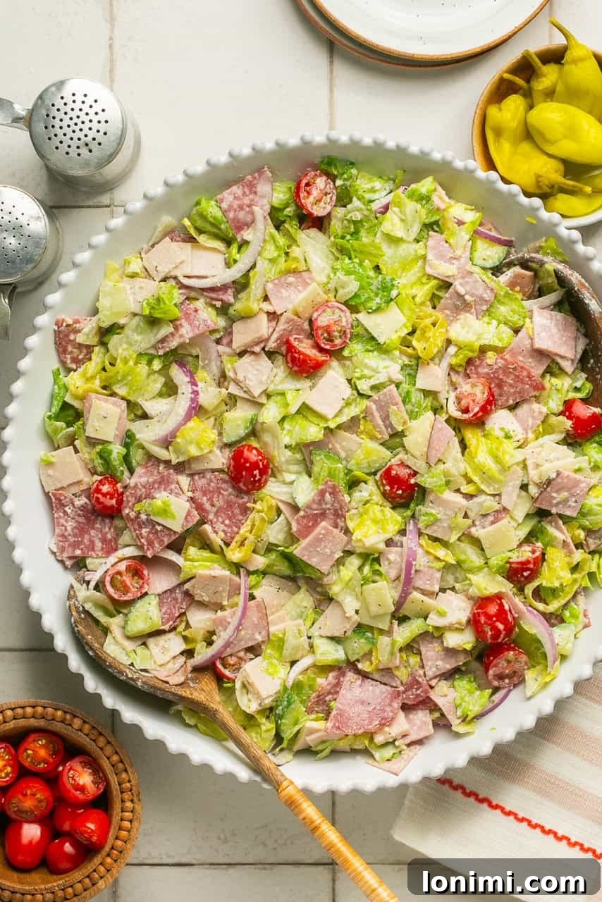 An overhead shot of a white salad bowl abundantly filled with the tossed Chopped Italian Grinder Salad, showing off its vibrant colors and textures.