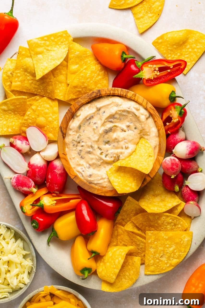 The Viral Protein-Packed Cottage Cheese Queso 7 An inviting overhead view of a festive platter featuring a central bowl of creamy cottage cheese queso, artfully surrounded by an assortment of colorful tortilla chips and fresh vegetables, perfect for sharing at any gathering.
