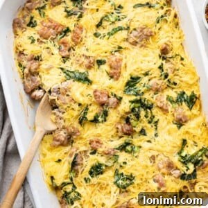 Tuscan Spaghetti Squash Casserole with sausage and kale in a white dish with a spoon