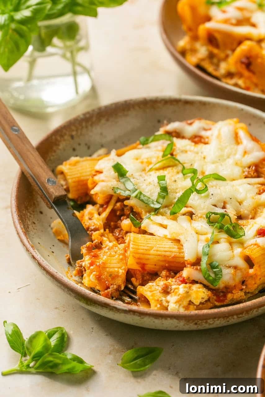 Effortless Cheesy Lasagna Bake 7 A fork taking a bite from a close-up section of Lazy Lasagna, highlighting the cheesy, meaty, and pasta layers.