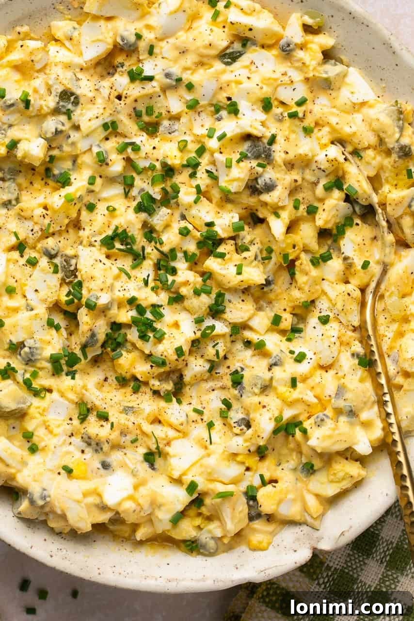 A close-up shot of a vibrant dill pickle egg salad in a rustic bowl, garnished with fresh dill.