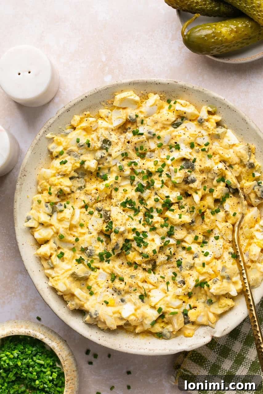 Dill pickle egg salad garnished with freshly chopped chives in a clear glass bowl, ready to serve.