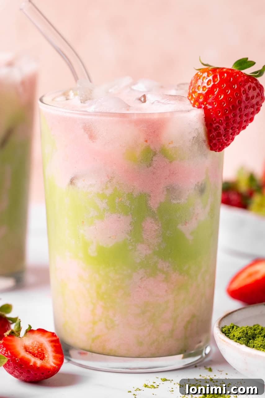 A refreshing iced matcha strawberry latte in a glass with ice cubes, ready to be enjoyed.