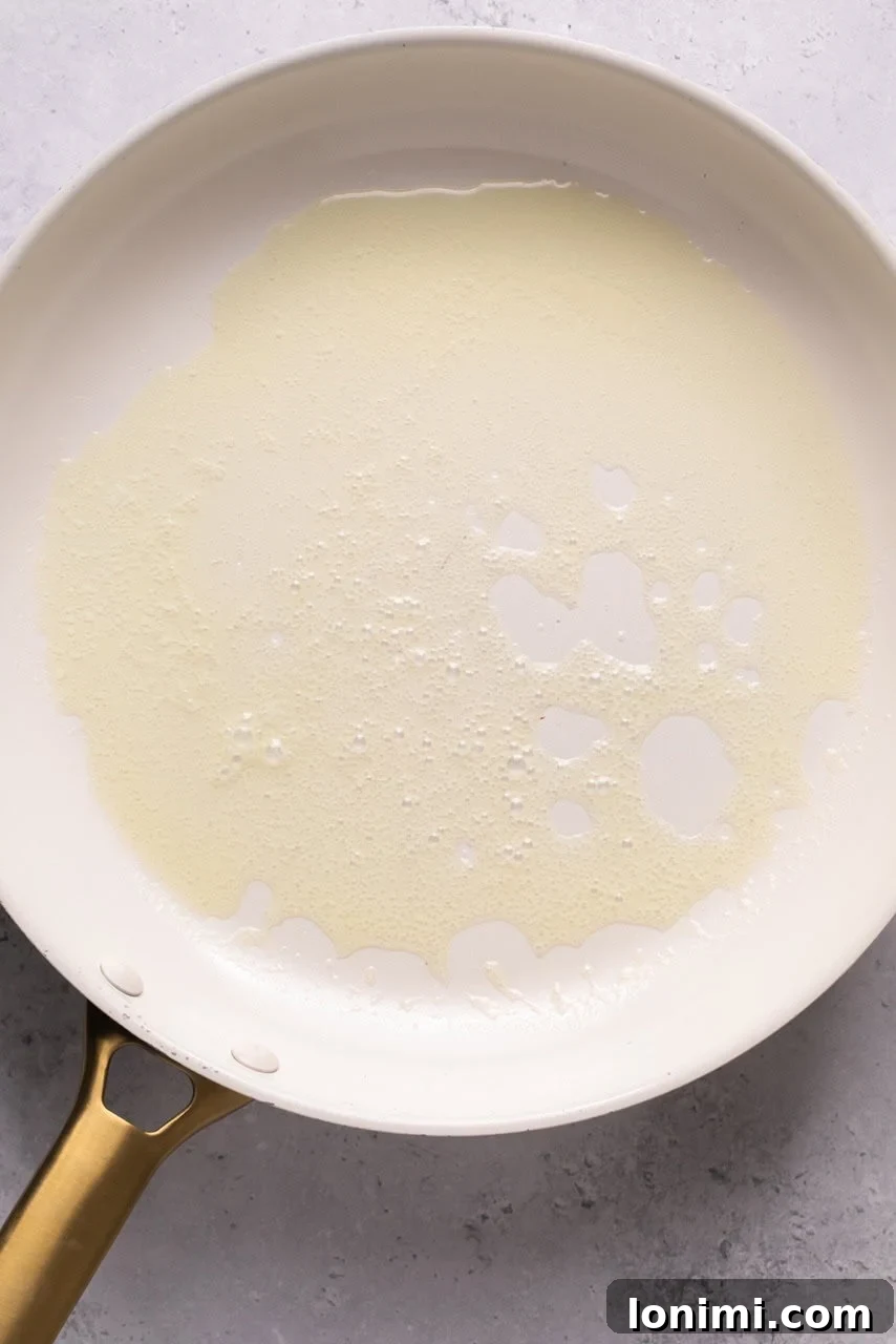 Butter melting and bubbling in a hot skillet, ready for apples.