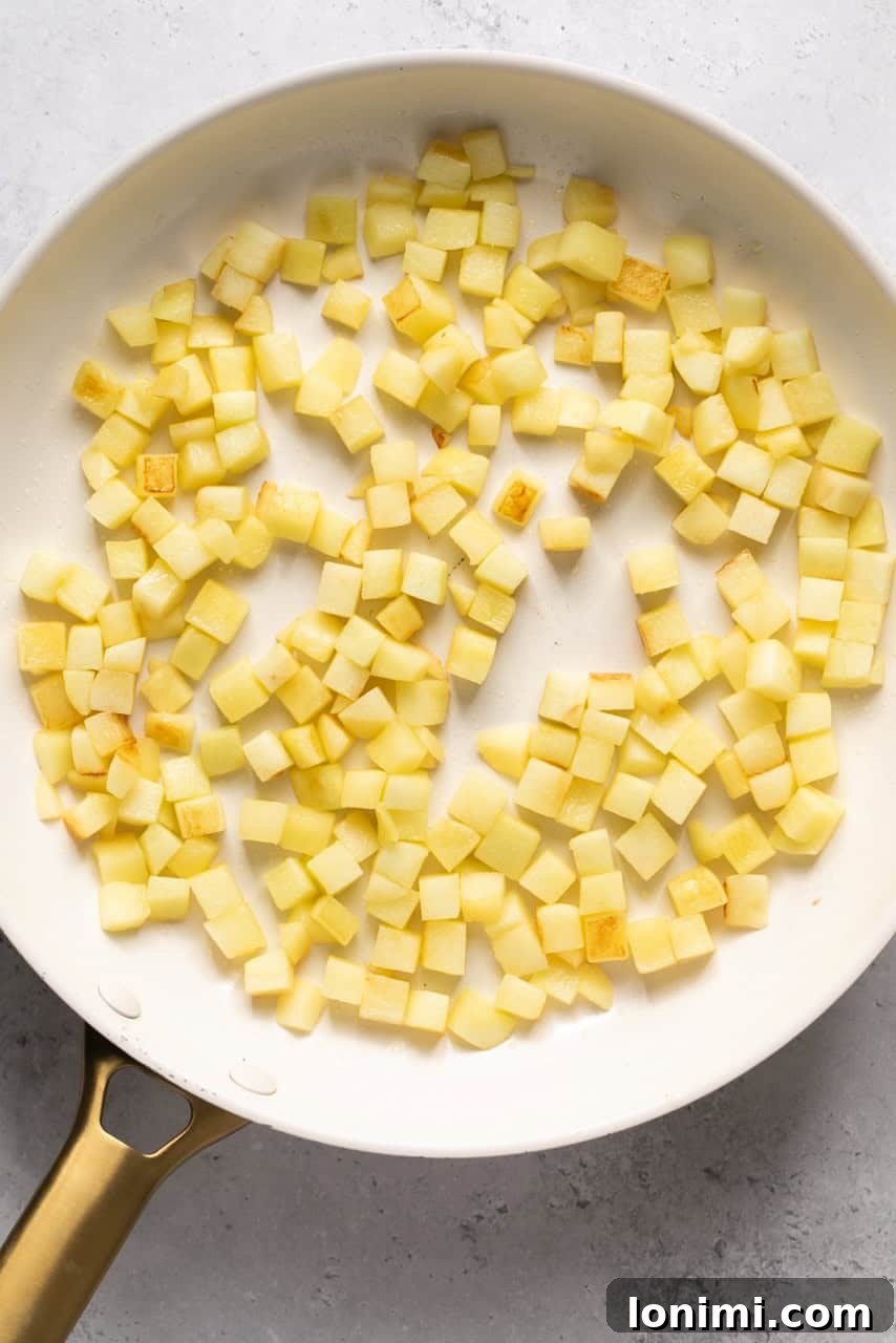 Chopped apples beginning to soften and brown in a skillet with melted butter.