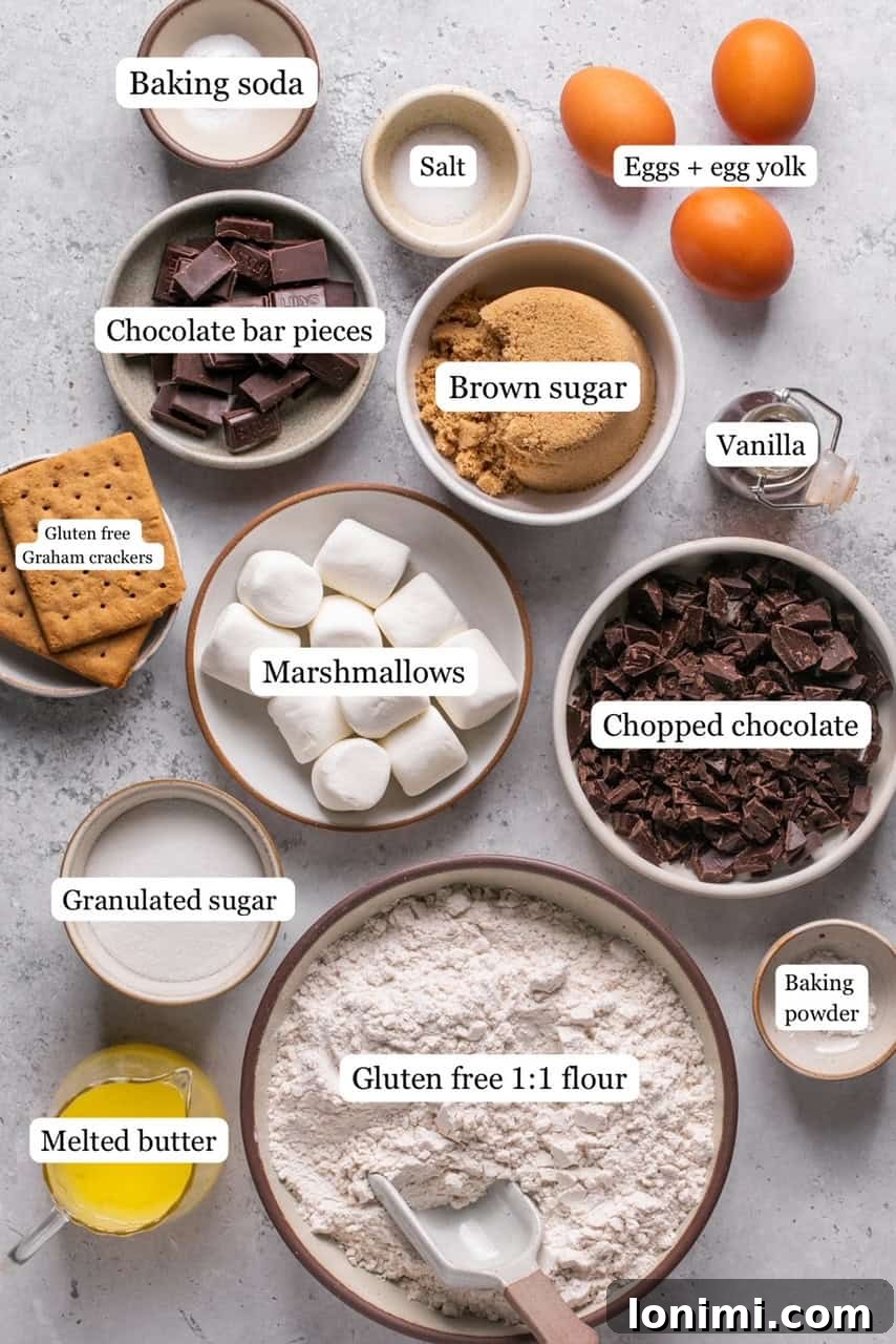 Recipe ingredients in small bowls and labeled, including butter, sugars, vanilla, eggs, gluten-free flour, leavening agents, chocolate bars, marshmallows, and graham crackers.