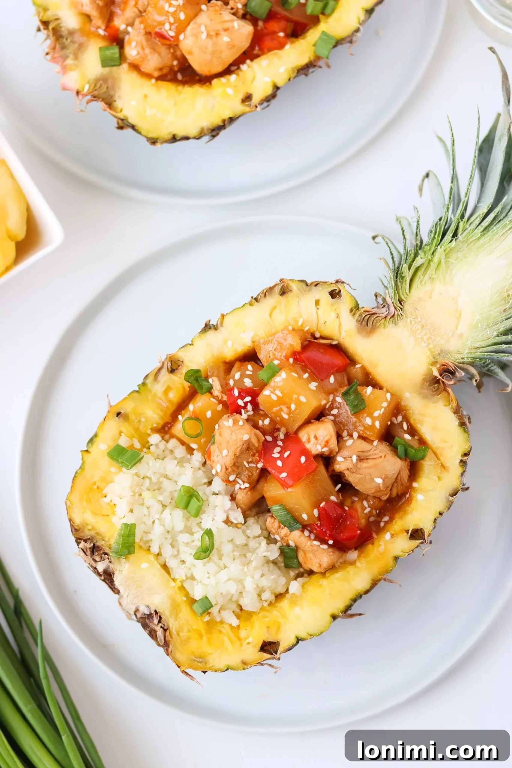 A vibrant, tropical serving of Whole30 Instant Pot Hawaiian Chicken, elegantly presented in a hollowed-out pineapple half, ready to be enjoyed.