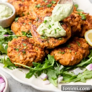 Spicy Southwest Keto Salmon Cakes with Creamy Avocado Aioli 10 Southwest salmon patties with avocado ranch aioli over greens on a white platter