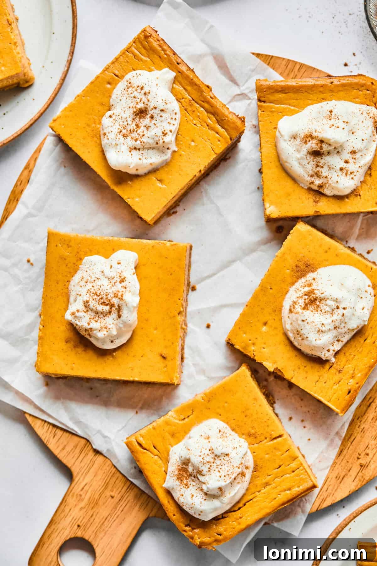 pumpkin pie cheesecake bars on a cutting board with parchment paper, ready to be served