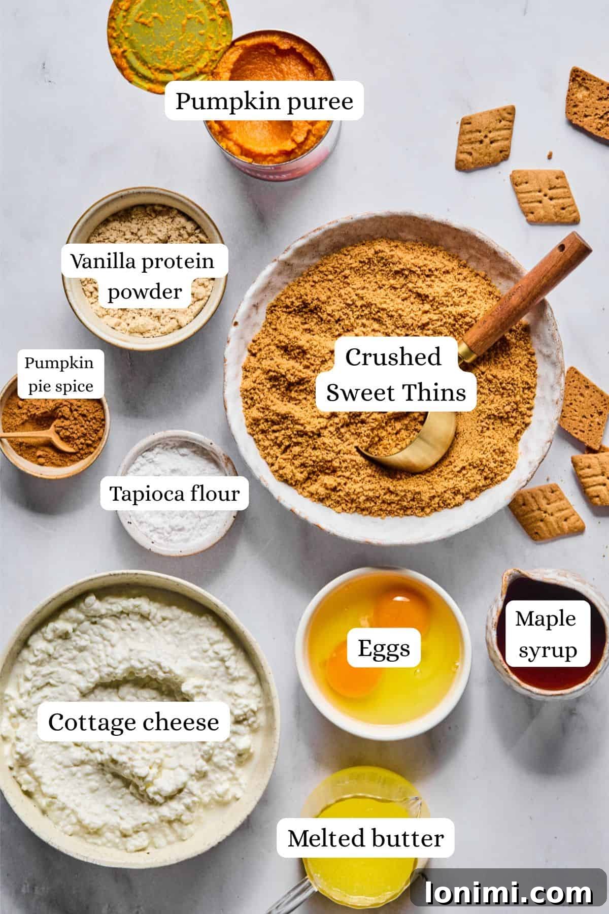 ingredients for pumpkin cheesecake bars in nesting bowls, including cottage cheese, pumpkin puree, and graham crackers