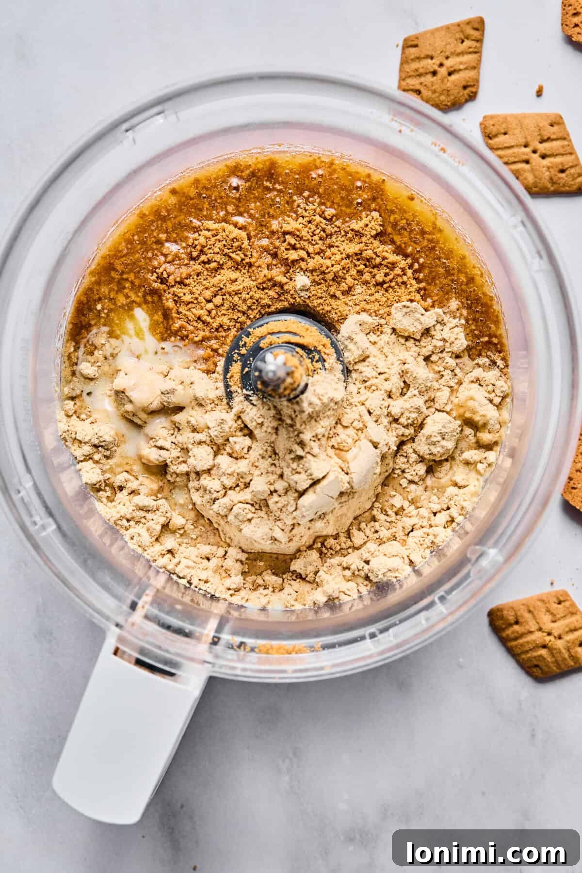 protein powder and graham cracker crumbs mixed in a food processor bowl