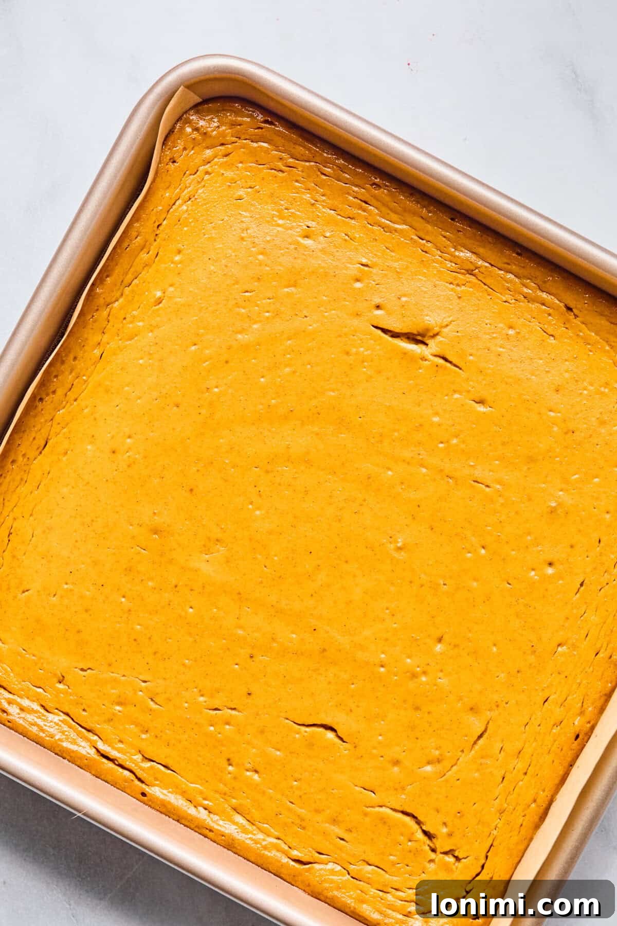 pumpkin cheesecake bars baking in a pan