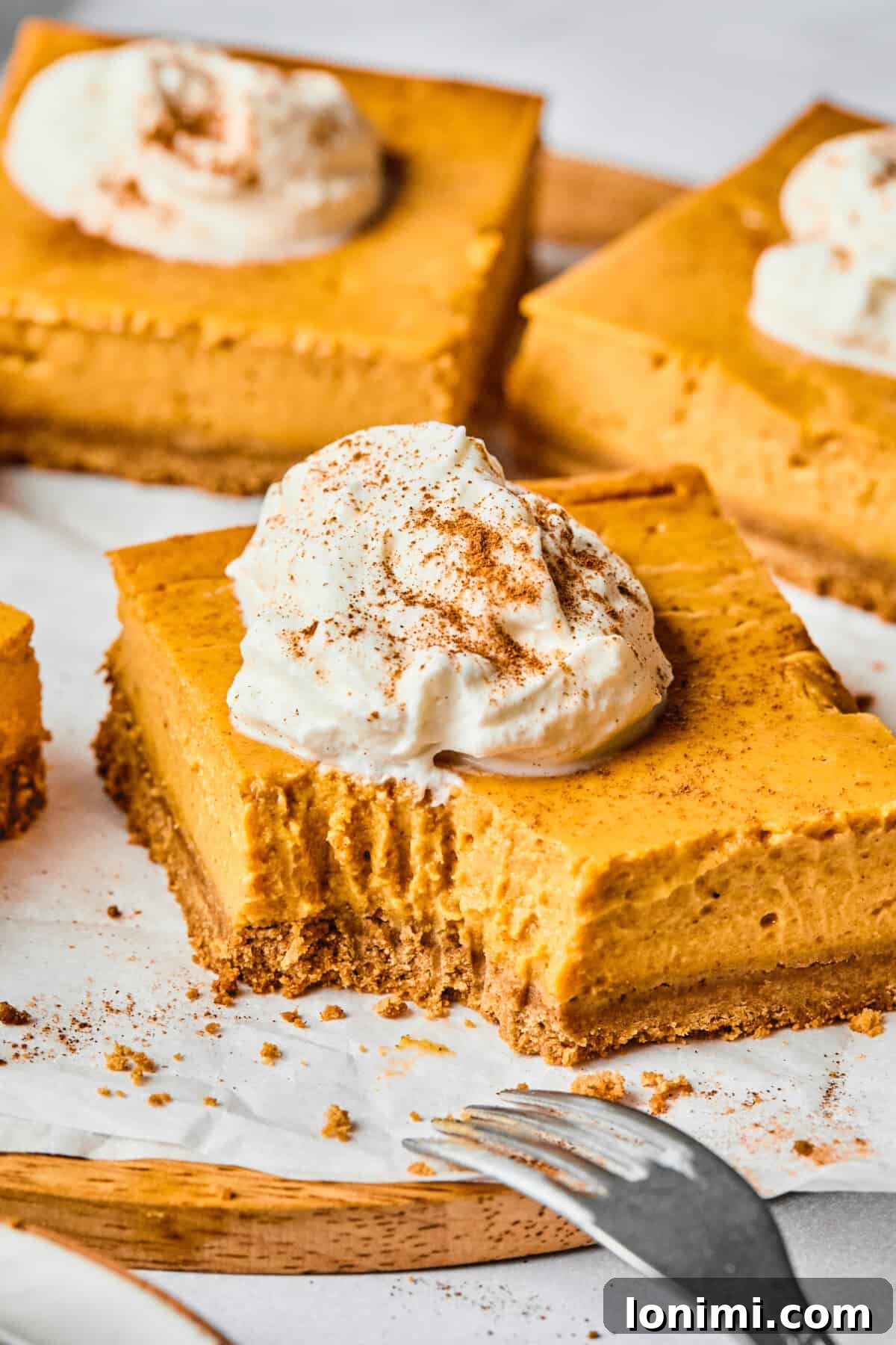 protein pumpkin pie bars with a bite taken out of one, showing the creamy filling and crust