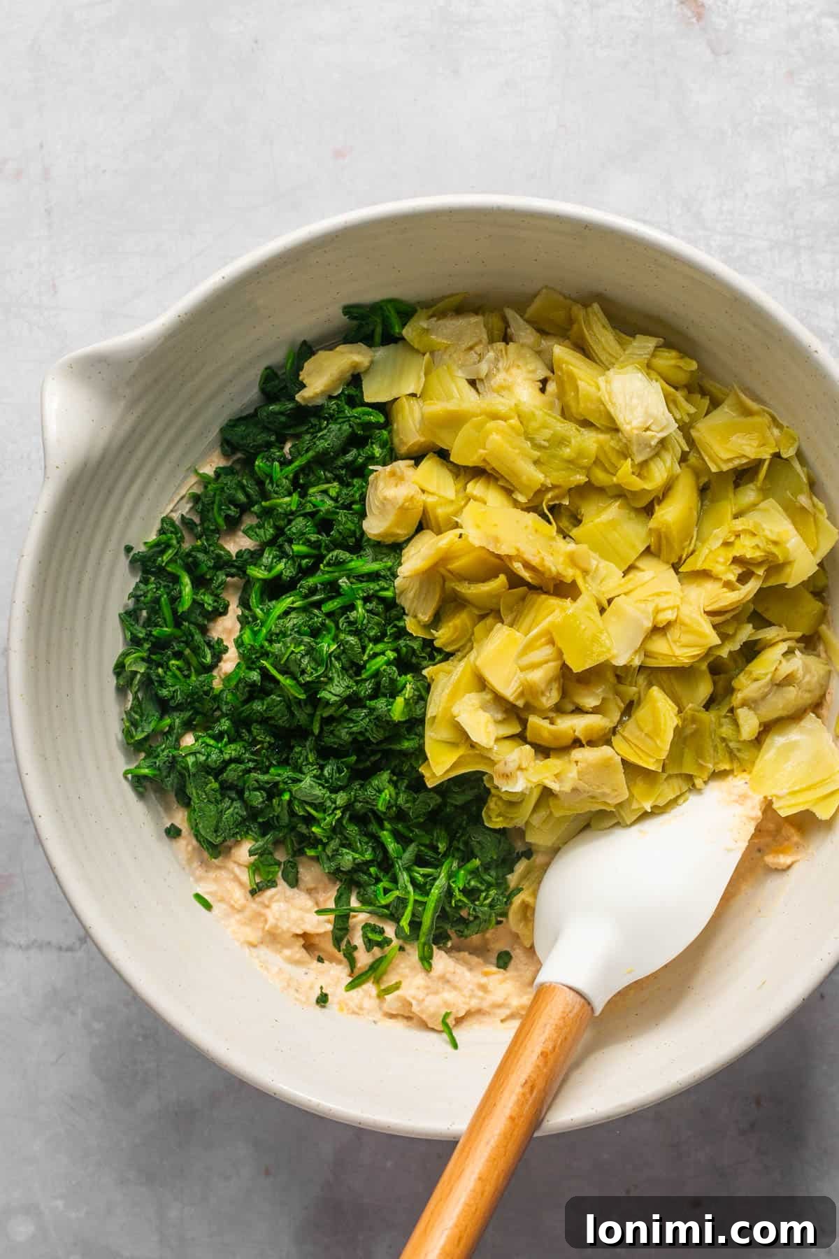 Decadent Mayo-Free Spinach Artichoke Dip 8 Chopped spinach and artichokes added to the creamy base in a large bowl