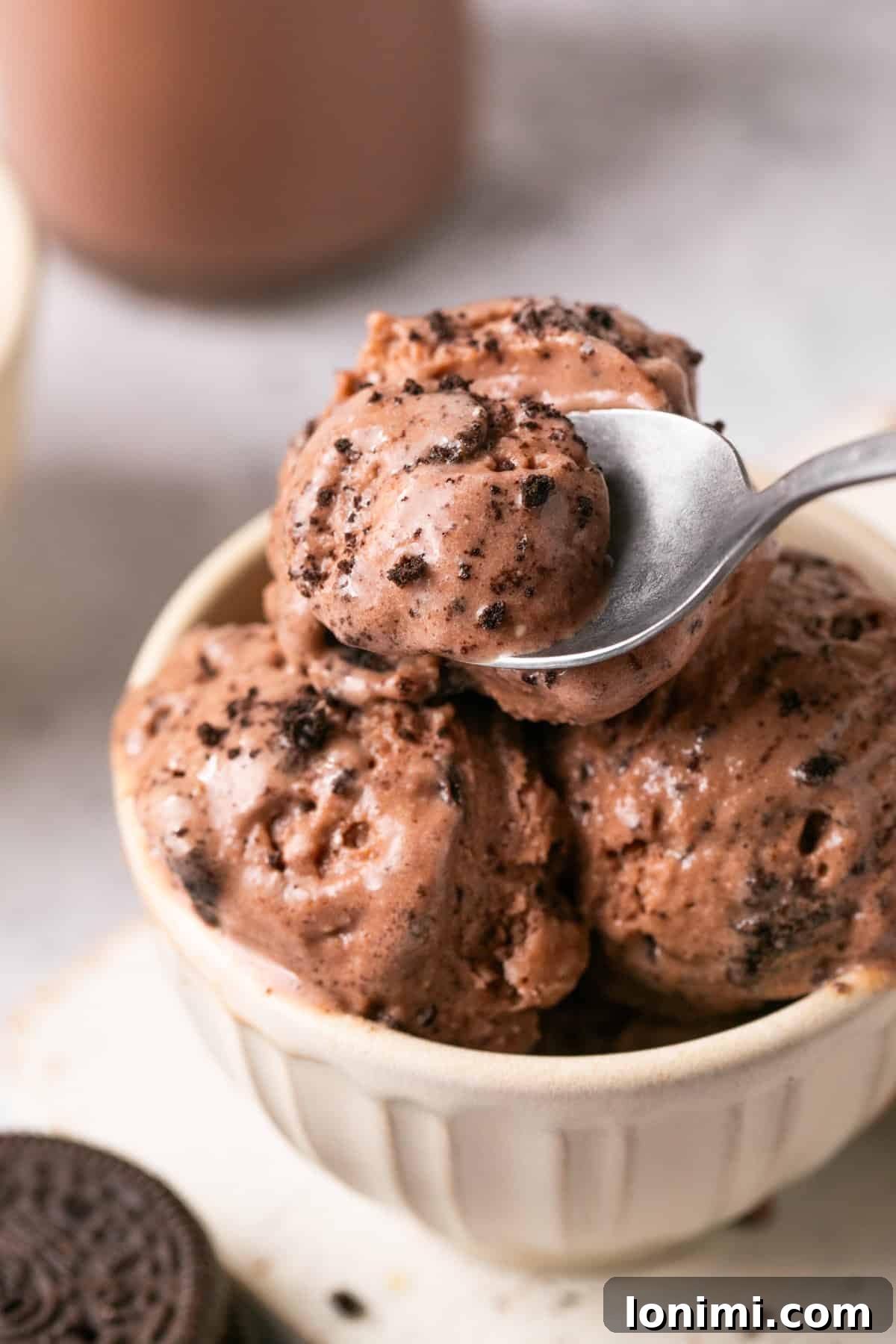 Easy Ninja Creami Protein Ice Cream with 4 Ingredients and 24g Protein 2 Ninja Cream chocolate protein ice cream in a white bowl with a spoon taking a scoop out