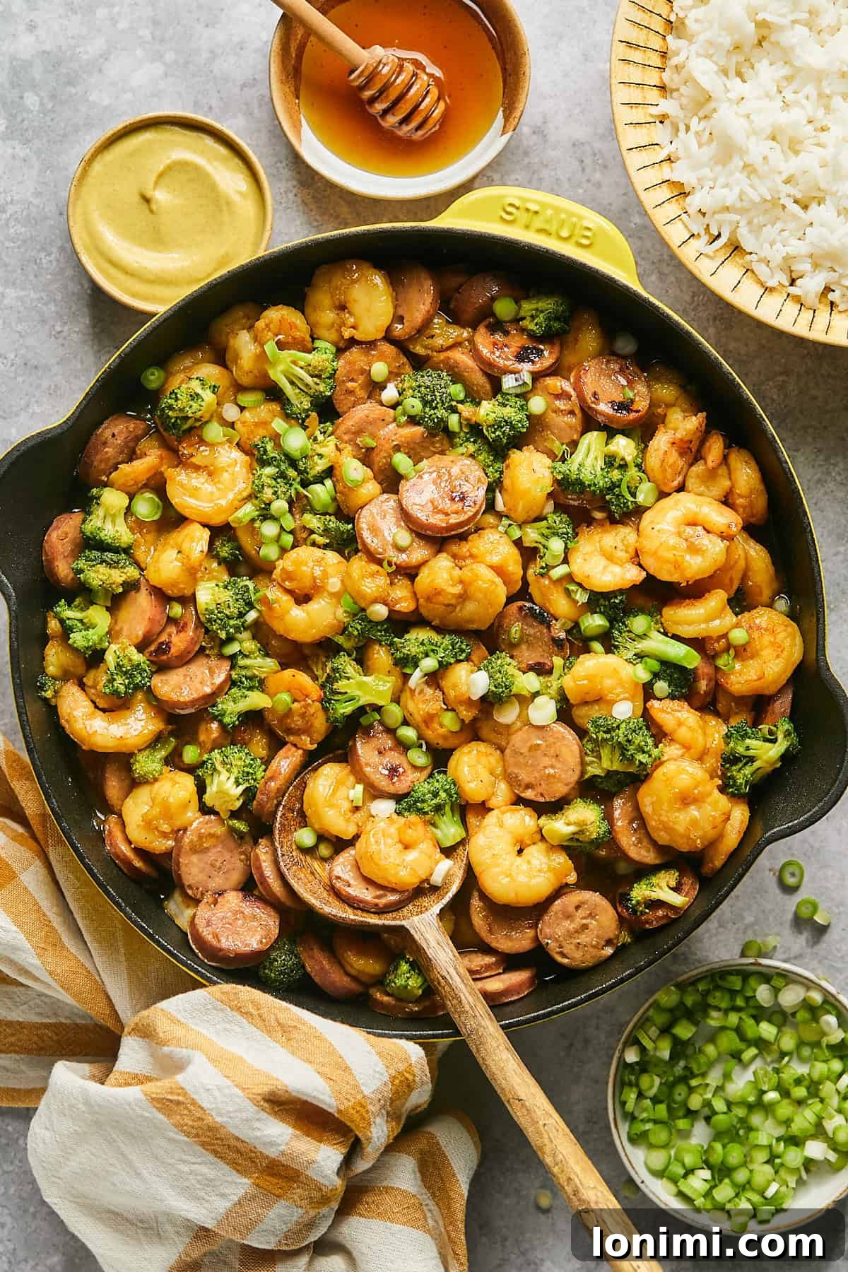 Gluten Free Hot Honey Glazed Shrimp and Sausage Stir Fry 2 Vibrant hot honey shrimp and sausage stir fry with crisp broccoli florets beautifully plated in a rustic yellow Staub skillet, ready to serve.