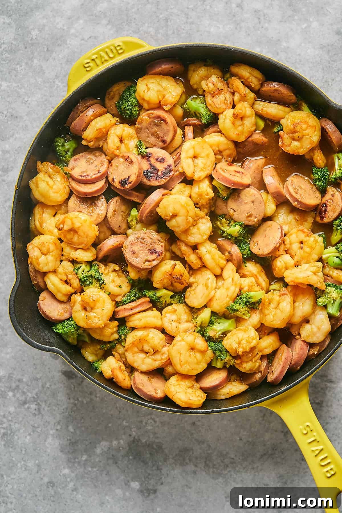Gluten Free Hot Honey Glazed Shrimp and Sausage Stir Fry 11 The finished hot honey shrimp and sausage stir fry, coated in a luscious glaze, tossed with broccoli in a vibrant yellow Staub pan, ready for serving.